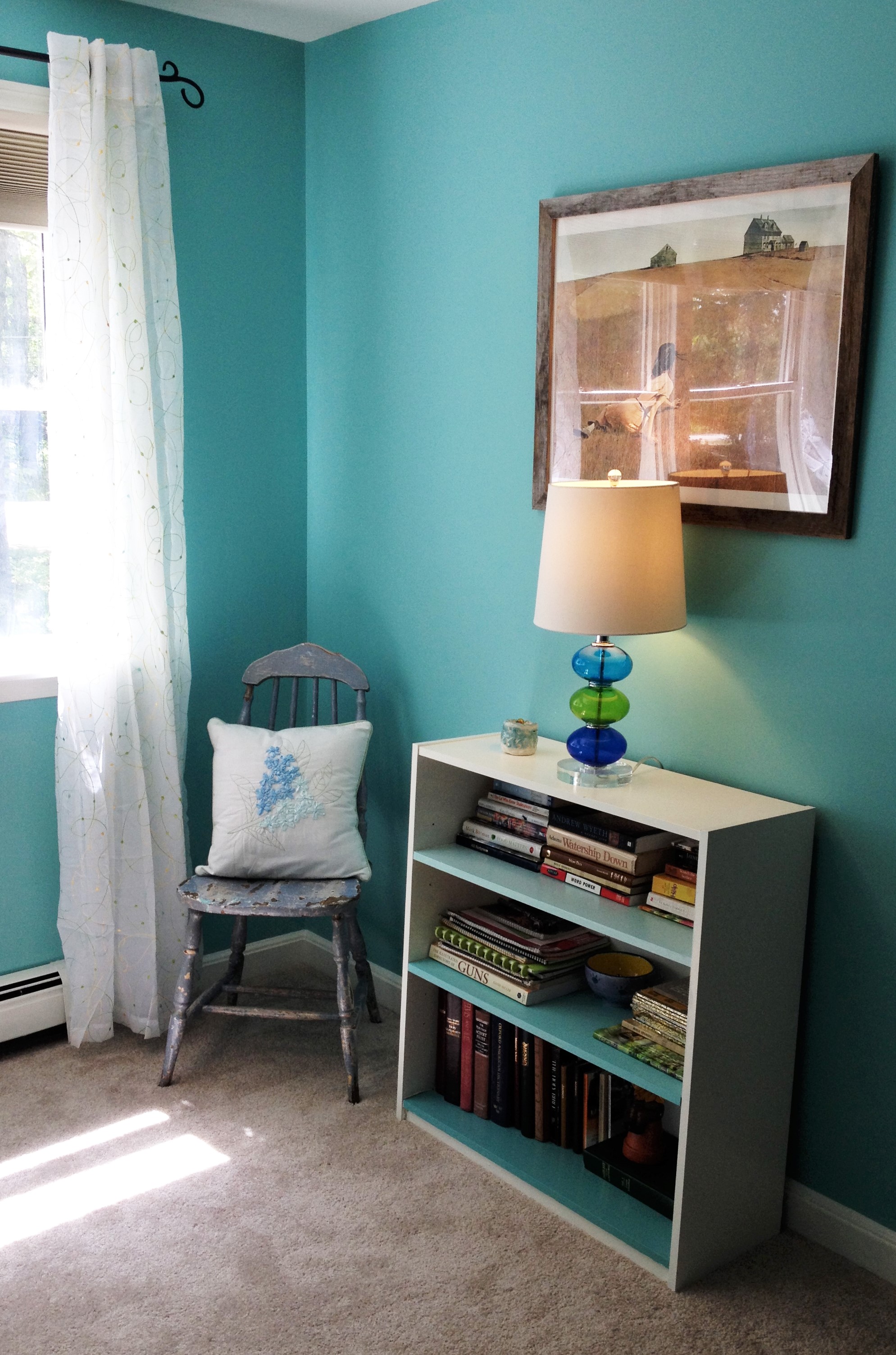 photo of chair, bookshelves with lamp and artwork